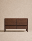 The Nell Wide Dresser by Wooden Stories, a dark wooden dresser featuring six drawers and exquisite timber joinery, is showcased against a plain beige background.
