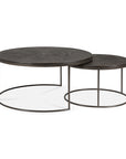 The Ethnicraft Nesting Coffee Table Slice Umber set includes two round tables with dark wooden tops and slim black metal frames, with the smaller table designed to slide partially under the larger one.