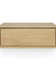 The Ethnicraft Nordic II Hanging Bedside Table is a rectangular, light wood floating drawer made from solid European oak with a minimalist design, shown front-facing on a white background. Ideal as a Nordic-style nightstand.