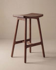 The Odd Counter Stool | Wood by Wooden Stories features a solid oak, Danish design with a curved seat and four angled legs joined by horizontal supports, shown against a plain beige background.