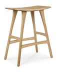 The Ethnicraft Osso Counter Stool - Oak boasts solid oak construction, a curved seat, and slim angled legs with horizontal supports, exemplifying minimalist modern design.
