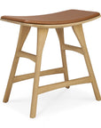 The Osso Dining Stool by Ethnicraft features angled legs, a curved brown leather seat, and smooth solid oak wood in a minimalist, modern European design.