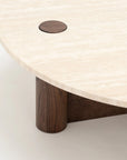 Close-up of the Pivot Coffee Table | Round - Wood & Stone by Wooden Stories, showcasing a light travertine top, solid oak leg, and small wooden inlay. Its minimal modern design stands out against a plain background.