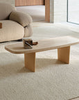 A minimalist living room with a light sofa, simple wooden coffee table on the Armadillo&Co Pebble Rug in Tofu (New Zealand wool), and a small décor piece on the table. Sunlight streams through sheer curtains.