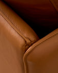 Close-up of the corner and seams of the Pensive Sofa | Leather by Wooden Stories, showcasing detailed stitching and the rich texture of its brown leather upholstery.