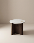 The Pivot Side Table | Wood & Stone by Wooden Stories features a white marble top, dark solid oak base, and a small brass inlay, all against a plain beige background. Inspired by the Danish Collection.