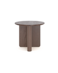 The Pivot Side Table by Wooden Stories features a round, dark wood design crafted from solid oak, with a thick flat top and three wide intersecting legs. Shown against a plain white background.