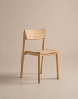 The Poise Dining Chair | Wood by Wooden Stories, featuring a minimalist solid oak design with a straight backrest and no armrests from the Danish Collection, is displayed on a neutral beige background.
