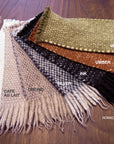 The HIMALAYAN HERMITAGE Radhi Rug in Moss is displayed on a wooden table, with its fringe length and color name clearly labeled on the image.