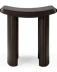 The Ethnicraft Roller Max Stool is a dark brown mahogany piece with a curved, smooth seat and three fluted cylindrical legs, displayed against a white background.