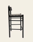 The Cesco Counter Stool by SOBU is a minimalist, modern piece crafted from solid black American ash, featuring a flat seat, small backrest, and squared legs, shown in profile against a plain light background.