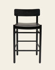 The Cesco Counter Stool - Black Ash by SOBU features a curved backrest and seat in solid American ash, with four straight legs and footrests, shown against a light beige background.