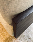 Close-up of SOBU's Woody Sofa (One Arm) in Espresso Ash and Fog, featuring a light beige cotton linen cushion beside its dark ash wood armrest, with a woven beige carpet underneath.