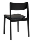 The Poise Dining Chair | Black Oak with Leather by Wooden Stories, designed by Patryk Koca, features a curved backrest and flat seat in black oak, shown from a rear angle.