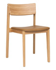 The Poise Dining Chair by Wooden Stories features a minimalist Danish design with a light oak frame, curved backrest, and flat leather seat for a modern touch.