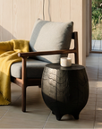 A cozy modern room with large windows, a wood-paneled wall, a cushioned bench, the SOBU Viking Lounge Chair in walnut with a mustard yellow throw, a small side table, and a black wall lamp. Natural light fills the space.