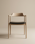 The SOBU Sven Dining Chair in White Ash with a black leather padded seat and curved backrest is centered against a plain beige background.