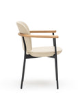 Side view of the Solace Dining Armchair | Leather by Wooden Stories, a modern beige leather upholstered chair with wooden armrests and a premium steel frame with black metal legs, set against a white background.