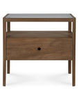 The Spindle Nightstand - Teak by Ethnicraft is crafted from FSC-certified teak and features four legs, a glass top, an open shelf, and a single drawer with a round hole handle.
