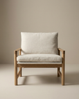 The Troubadour Lounge Chair by Wooden Stories features a solid oak frame and light beige fabric upholstery on its cushioned seat and backrest, showcased against a plain beige background.