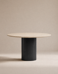 The Tathra Round Dining Table | Stone Top by Wooden Stories features a light beige stone top and a thick, cylindrical black base, crafted to contract grade standards and shown against a plain neutral background.