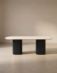 The Tathra Ellipse Dining Table by Wooden Stories features a minimalist rectangular stone top with rounded edges and two solid oak pedestal legs, showcasing European craftsmanship against a neutral background.