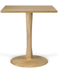 The Ethnicraft Torsion Square Dining Table in solid European oak features a square top, single central pedestal leg, and round base, shown against a plain white background.
