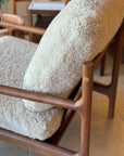 A close-up of the SOBU Viking Lounge Chair - Walnut, featuring solid walnut construction and soft, cream textured cushions, set in a warmly lit room with other SOBU furniture and wooden accents in the background.