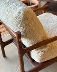 A close-up of the SOBU Viking Lounge Chair - Walnut, featuring smooth, rounded solid walnut and plush cream textured cushions, with cozy upholstery highlighted in a sunlit room.