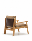The Wren Lounge Chair | Leather by Wooden Stories features tan leather cushions and a dark brown leather backrest, all beautifully crafted from solid walnut. Shown from an angled rear view against a white background, this chair evokes the timeless elegance of classic Danish furniture.