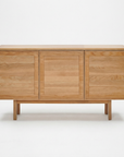 The Yorke Sideboard by Wooden Stories is a minimalist solid oak piece with three doors, a light natural finish, and Scandinavian design. It stands on four sturdy legs and is pictured against a plain white background.