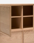 The Yorke Highboard by Wooden Stories is a wooden cabinet with four square compartments, two open doors, simple clean lines, and a natural light finish—capturing Scandinavian design against a plain backdrop.
