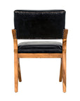 The Dolores Chair by Noir Trading Inc. is shown from the back, featuring black leather upholstery, a wooden frame, and metal stud accents that highlight its mid-century design.