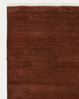 The Armadillo&Co Agra Rug - Burnt Umber is a rectangular, dark reddish-brown rug with subtle texture and white tassel fringe along the top edge, displayed on a plain light background to highlight its artisanal craftsmanship.