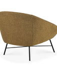 The Ethnicraft Barrow Lounge Chair - Ginger features brown textured upholstery and slim black metal legs, seen from a rear side angle for a subtle vintage vibe.