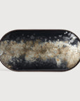 The Black Organic Glass Tray - Oblong / Medium by Ethnicraft features dark edges and a marbled, mineral-inspired pattern in black, brown, beige, and white—resembling hand-painted glass—against a plain light background.