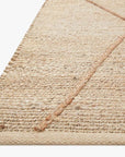 Close-up of the Bodhi Rug - Ivory / Natural Abstract by Loloi, featuring a hand-knotted 100% jute construction with a subtle textured pattern and diagonal lines. The woven beige rug is shown against a white background.