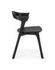 Side view of the Ethnicraft Bok Dining Chair - Black Oak, featuring solid oak construction, angled legs, a gently curved backrest, and a flat seat, set against a white background.