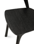 Close-up view of the Ethnicraft Bok Dining Chair - Black Oak, highlighting the seat and part of the legs, with visible wood grain texture and a clean, minimalist design.