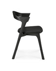 Side view of the Ethnicraft Bok Dining Chair - Black Oak with Leather, featuring a curved backrest and angled legs, shown against a white background.
