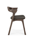 Side view of the Ethnicraft Bok Dining Chair - Brown Oak with Leather, featuring a curved backrest and black semi-aniline leather seat, shown against a plain white background.