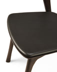 Close-up of the Ethnicraft Bok Dining Chair - Brown Oak with Leather, showing its solid oak legs and dark brown semi-aniline leather cushioned seat, set against a white background.
