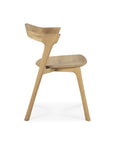 Side view of the Ethnicraft Bok Dining Chair - Oak, featuring a curved backrest and seat, clean minimalist lines, and angled legs, displayed against a plain white background.