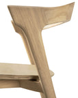 Close-up of the Ethnicraft Bok Dining Chair - Oak, showcasing its smooth, angular lines and natural oak grain. Focus is on the solid oak backrest and seat, emphasizing the minimalist design.