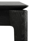 Close-up of the Ethnicraft Bok Dining Table - Black, highlighting the textured European oak grain on its sturdy leg and the smooth, angled edge of its tabletop.