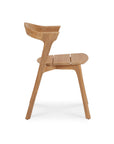 Side view of the Ethnicraft Bok Outdoor Dining Chair in natural teak, featuring a curved backrest, angled legs, and flat seat, crafted from FSC certified wood, inspired by the Ethnicraft outdoor collection, shown against a white background.