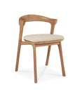 The Ethnicraft Bok Outdoor Dining Chair, made from FSC certified natural teak, has four angled legs, a curved backrest, and a light beige cushion seat. It is shown against a plain white background.