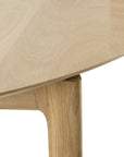 Close-up of the Ethnicraft Bok Round Extendable Dining Table in oak, showing the smooth tabletop-leg joint and natural wood grain, which highlights its minimalist design.