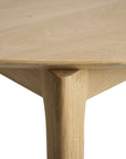 Close-up of the Bok Round Extendable Dining Table - Oak by Ethnicraft, highlighting the smooth finish and precise joinery where the solid oak tabletop meets the leg, set against a white background.