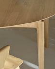 Close-up of the Ethnicraft Bok Round Extendable Dining Table in oak, featuring rounded edges and minimalist design, paired with a matching chair on a light floor that highlights the natural wood grain.